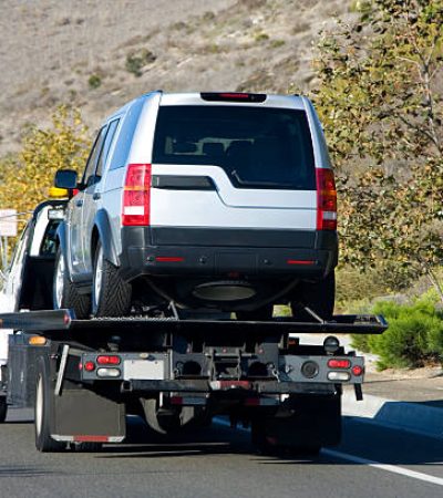 A tow truck towing a silver suv.