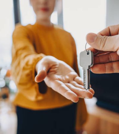 Close-up shot of a real estate agent giving a young Asian woman the keys to her new home. Home ownerships concepts