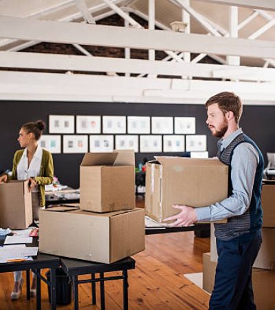 Group of business people packing cardboard boxes in creative office