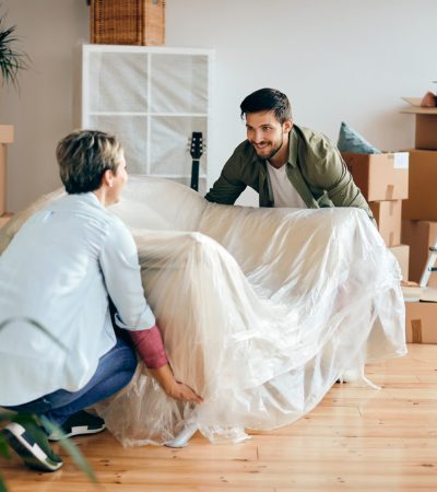 Happy couple bringing the furniture in their new home. Focus is on man.