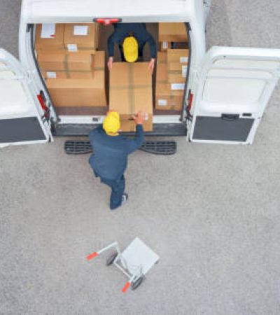 Overhead view of male and female delivery person loading cardboard boxes from van.